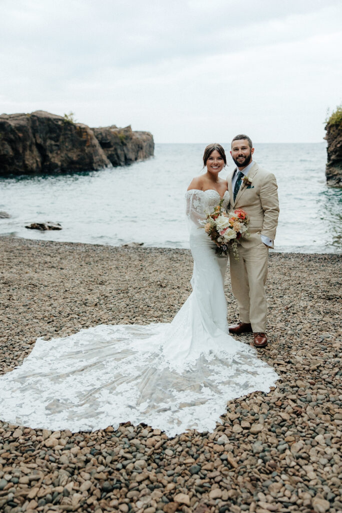 bride and groom standing in front of Lake Superior