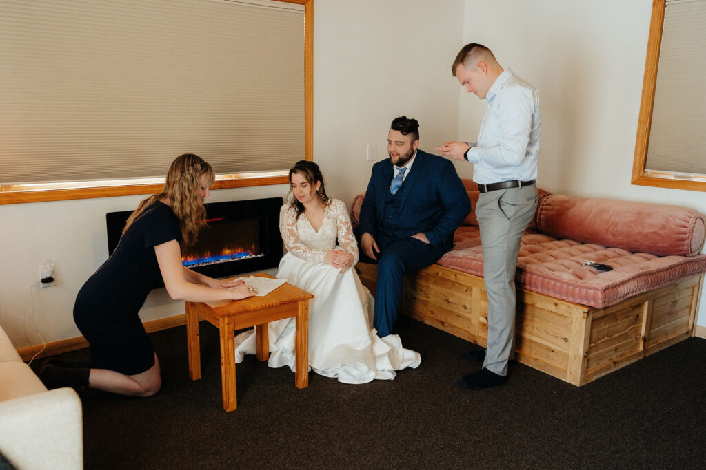 bride and groom with their two witnesses signing their marriage license inside a cabin